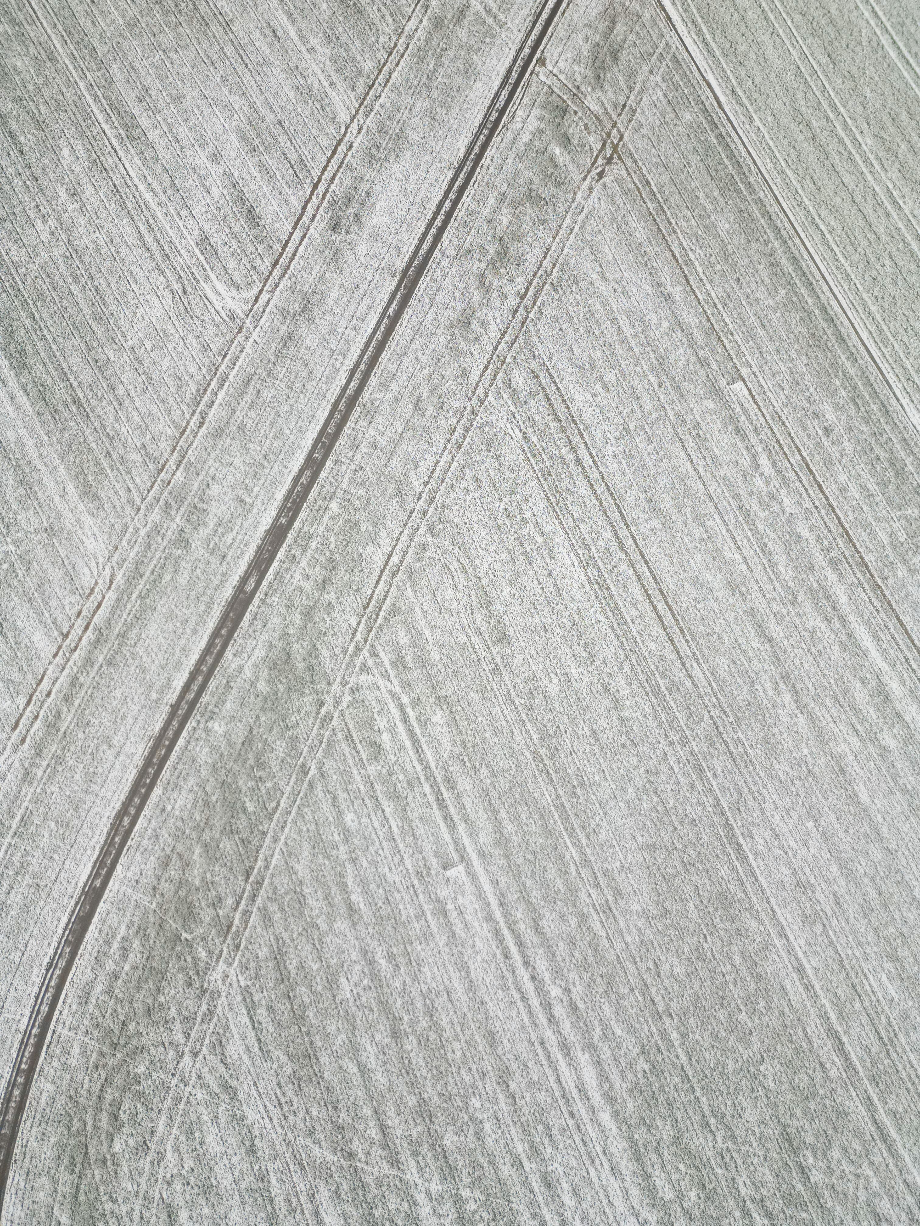 Aerial view of snow-dusted fields with geometric tracks — Emiel Vansteenbrugge on Pexels