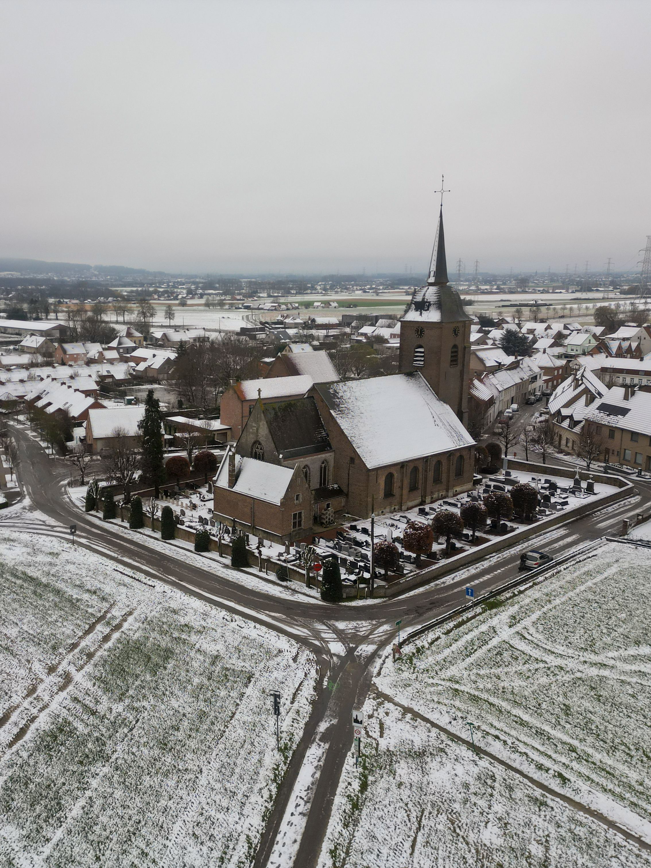 Aerial view of a snow-covered church surrounded by a quaint town in winter.