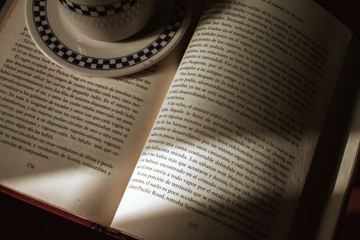 An open book with a coffee cup, capturing a serene reading atmosphere indoors.
