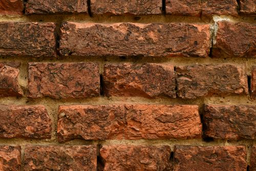Free Close-up of a textured red brick wall highlighting rough surfaces. Stock Photo