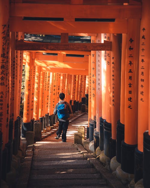 Man Walking through Fushimi Inari Taisha Gates 