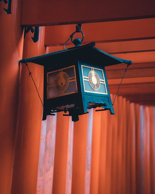 Free Close-up of a traditional lantern hanging among the iconic red Torii gates in a Japanese shrine. Stock Photo