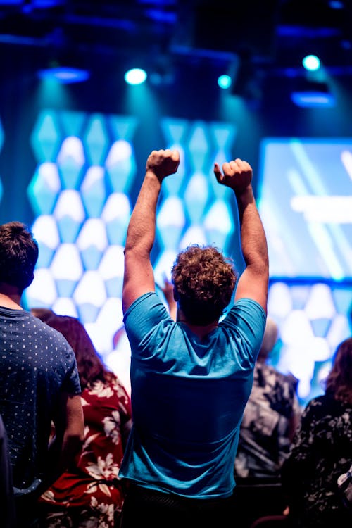 Man Standing in a Gathering of People with his Raised Arms 