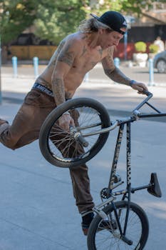 Shirtless BMX rider performs a stunt in an urban area, showcasing skill and tattoos.