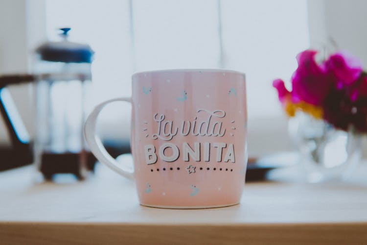 Pink And White Ceramic Mug On Brown Wooden Table