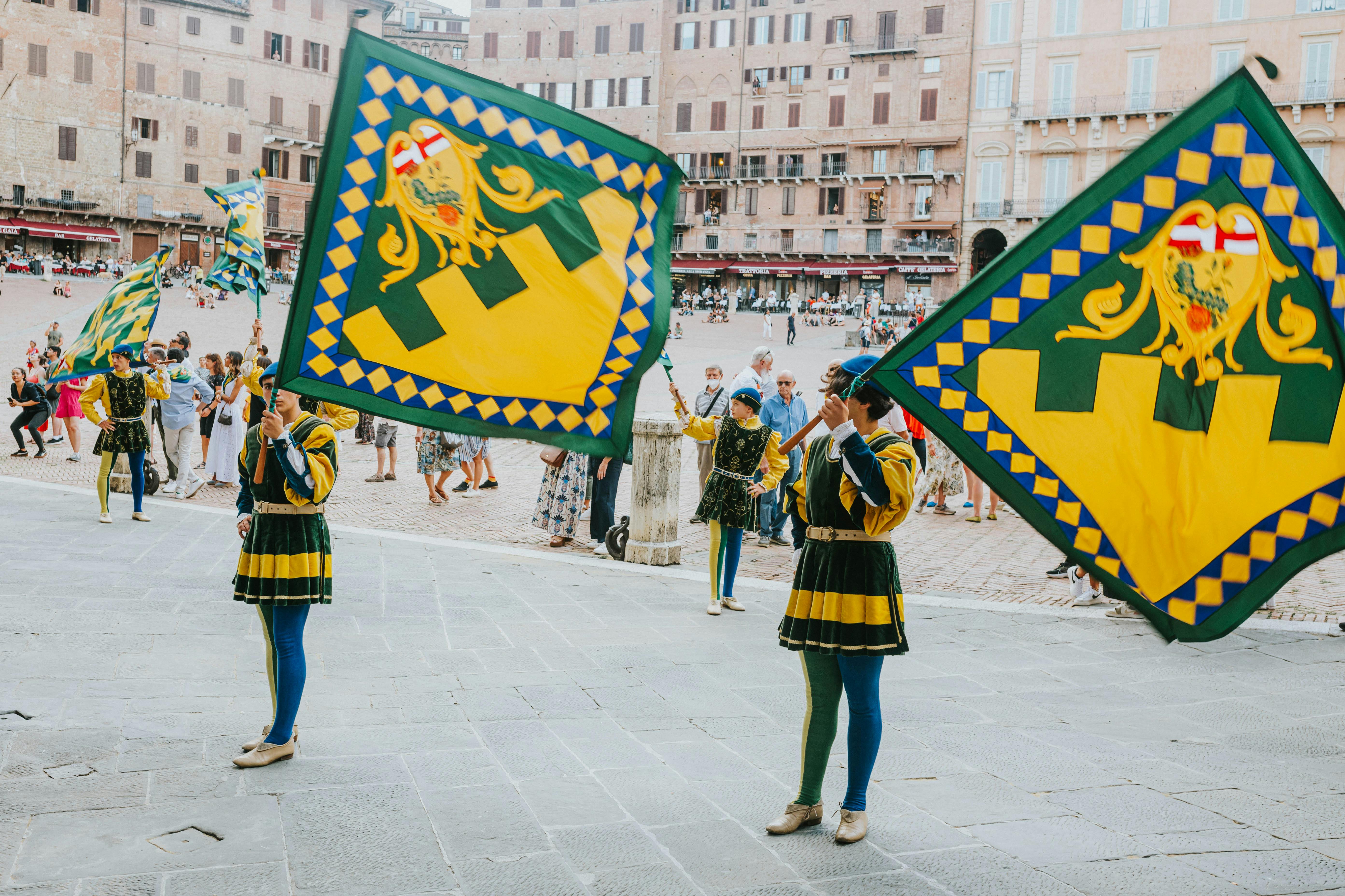 people in traditional costumes holding flags and performing in a city square