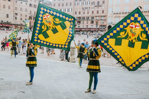 Free Colorful parade with flag bearers in traditional costumes at an Italian festival in a historic square. Stock Photo