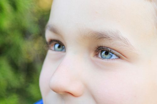 Free A close-up view of a child's blue eyes and soft features in natural light. Stock Photo
