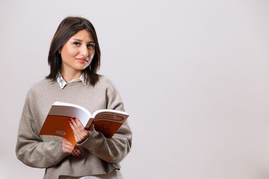 Portrait of a young woman reading a book in a studio setting, embodying a professional and stylish look.