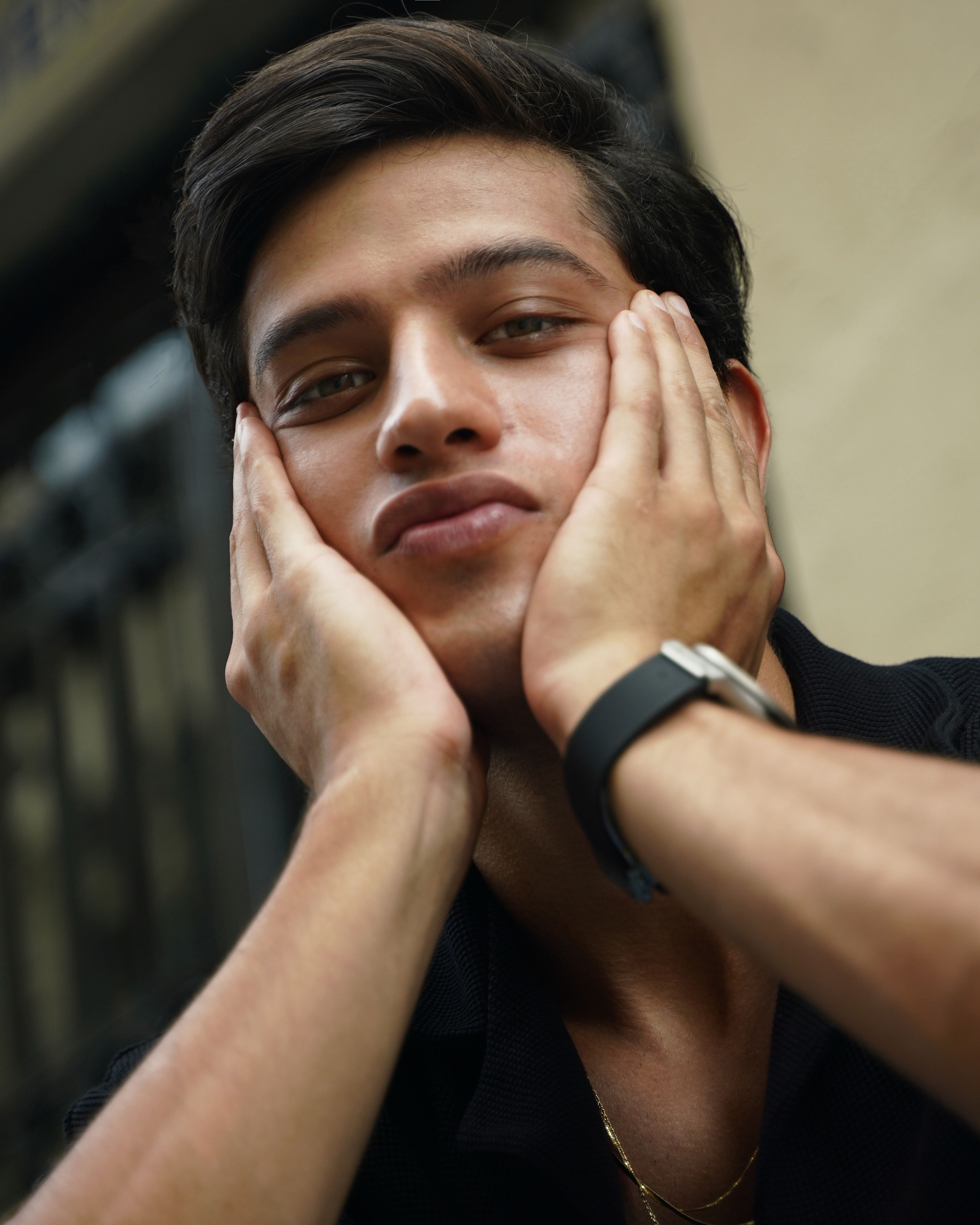 A young man in a thoughtful pose outdoors, showcasing facial expression and fashion.