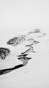 A serene black and white winter landscape featuring a winding river through snowy terrain.