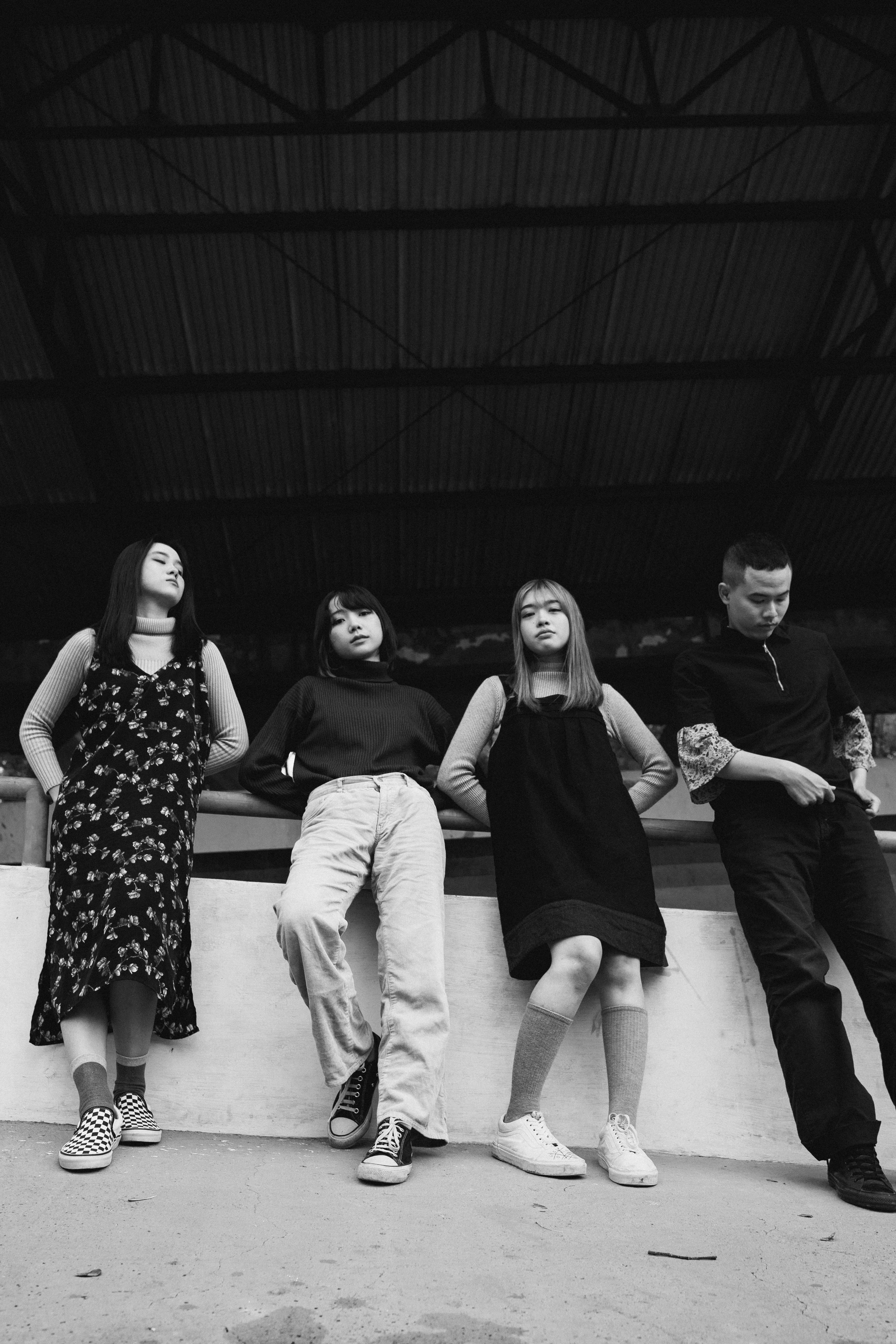 Black and white image of four young adults posing in an industrial space.