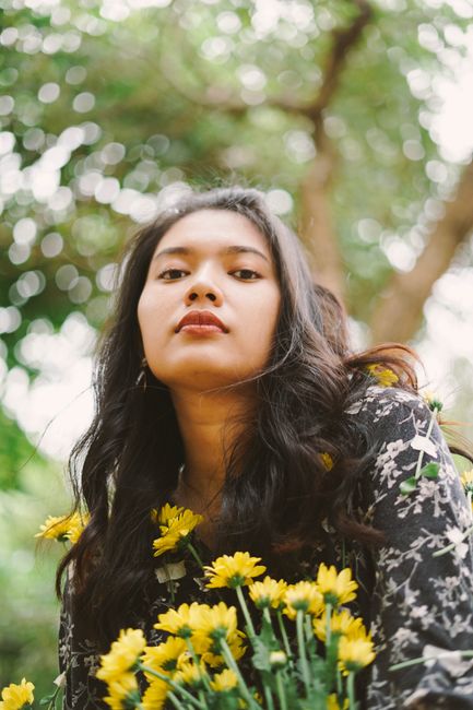 Portrait of a woman with flowers against a blurred natural backdrop.