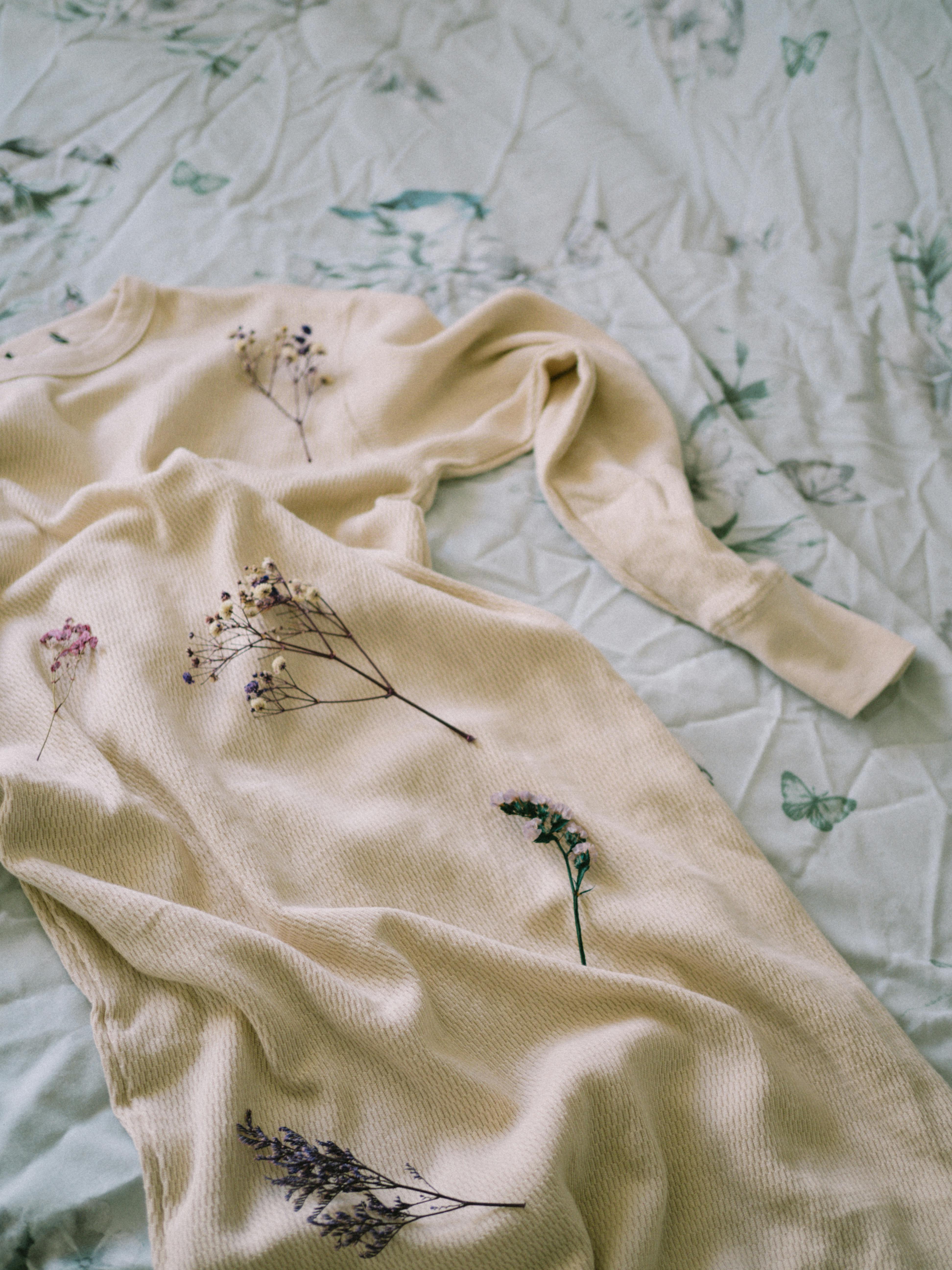A soft beige dress with floral prints elegantly arranged on a floral-patterned bedspread.