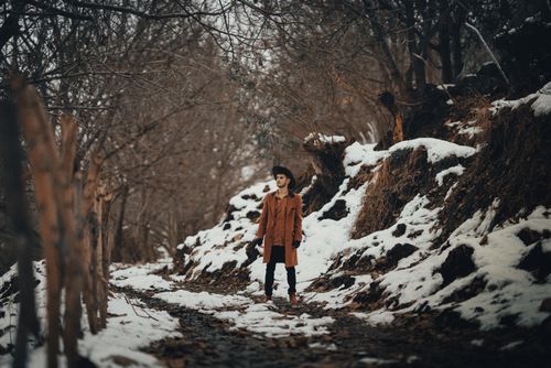 Free A well-dressed man stands in a snowy forest, showcasing winter fashion with a dramatic flair. Stock Photo