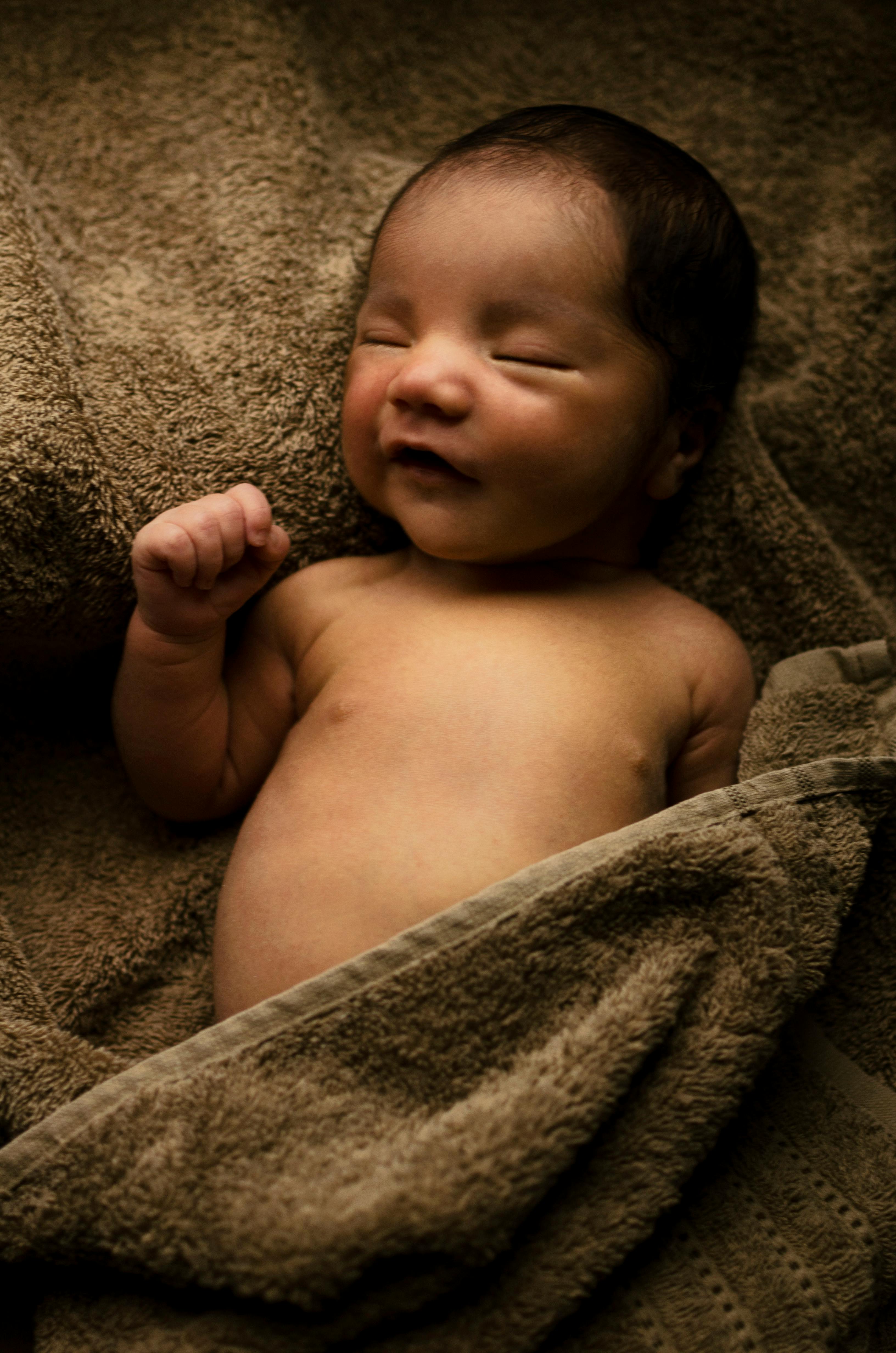 baby wrapped by brown bath towel