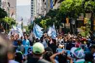 阳光明媚的日子里，城市里人们举着旗帜和标语，抗议活动热闹非凡