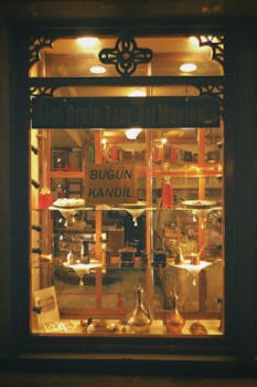 A warmly lit antique store window exhibiting various items during the night.