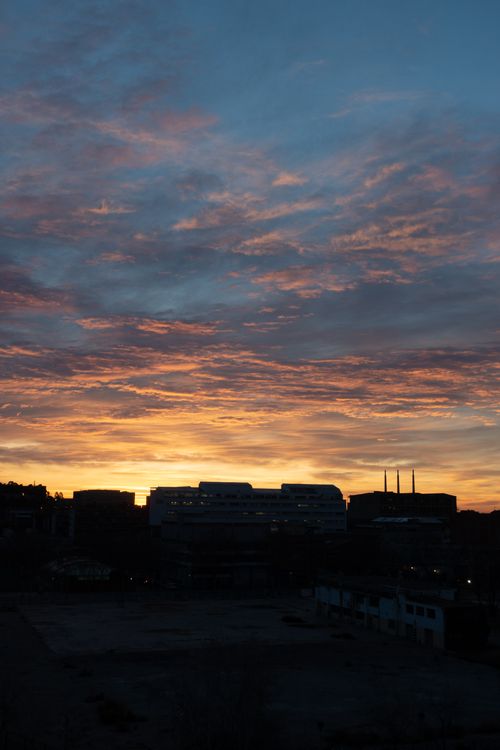 Free A city skyline silhouette with a vibrant sunset sky, creating a dramatic and calming scene. Stock Photo