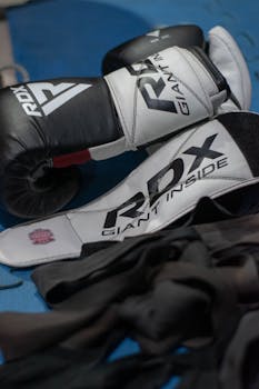 RDX boxing gloves displayed on a blue mat with hand wraps, perfect for sports and training themes.