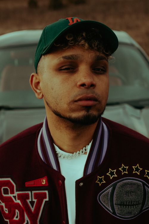 Free Portrait of a fashionable young man in a green cap standing in front of a car. Stock Photo