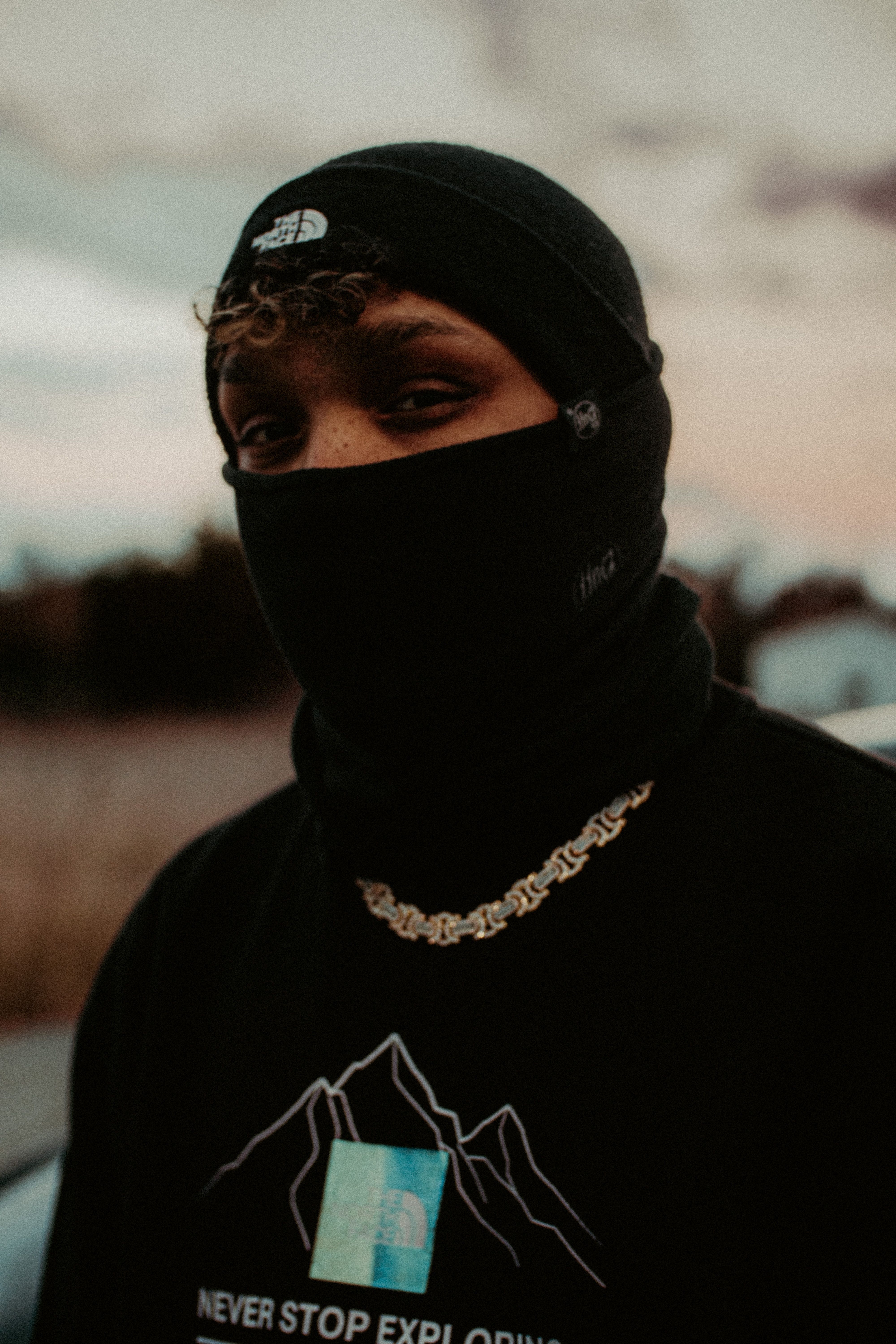 Mysterious portrait of a man in black clothing with a mask and chain necklace.