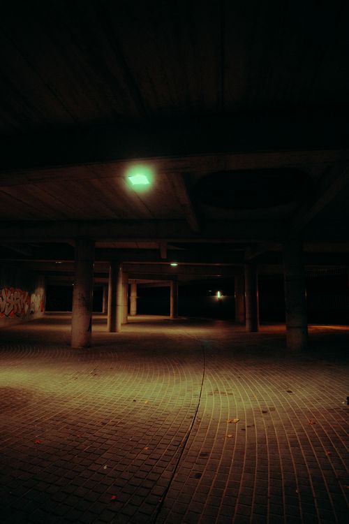 Free Atmospheric view of a dimly lit underground parking area with graffiti on the wall. Stock Photo