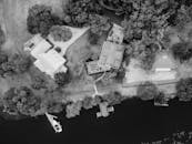 黑白航拍展现了河边的房屋，码头区被葱郁的树木环绕