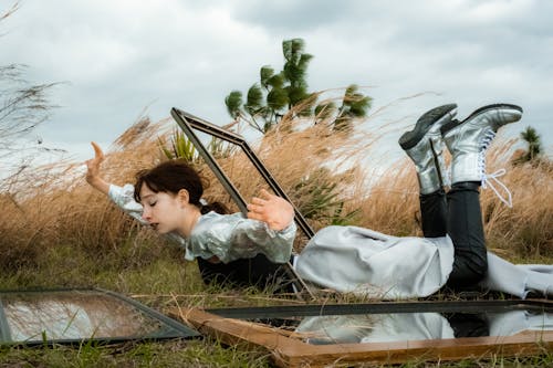 Free Woman Lying Down in Frame on Field with Mirrors around Stock Photo