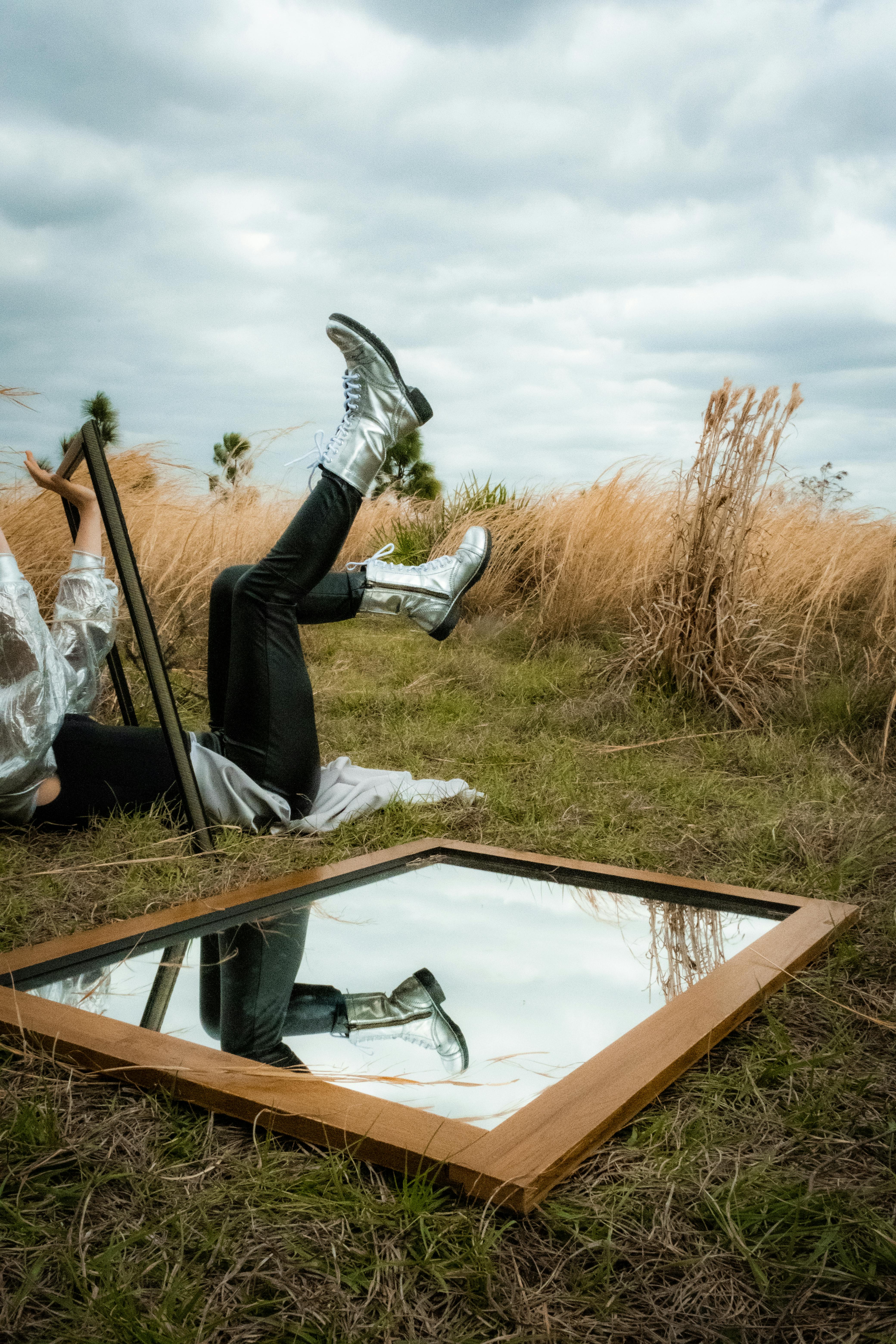 An artistic fashion scene featuring silver boots and a mirror reflection in rural Florida.