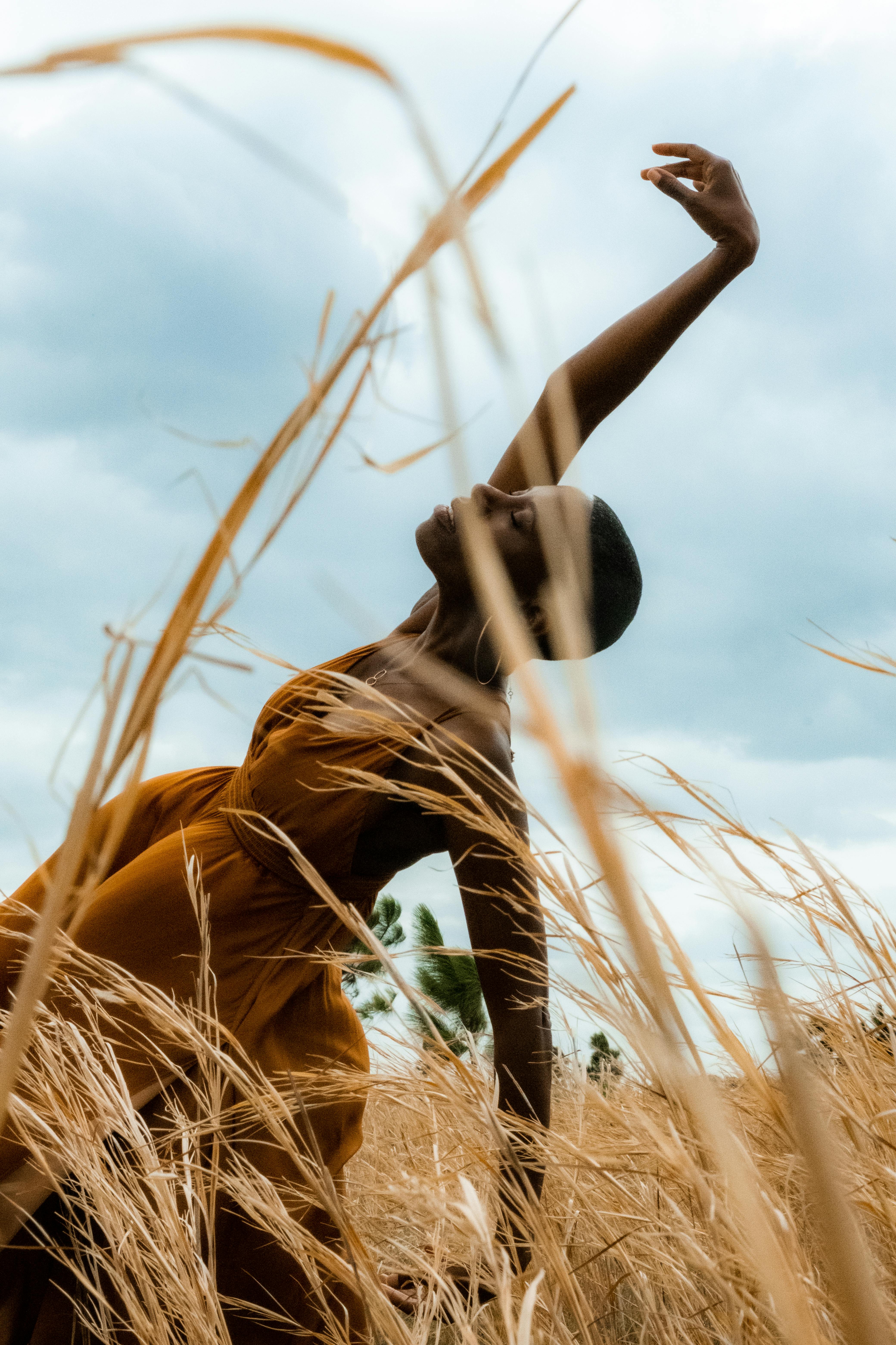 African woman gracefully dances among golden wheat, capturing summer's beauty in Kissimmee, FL.