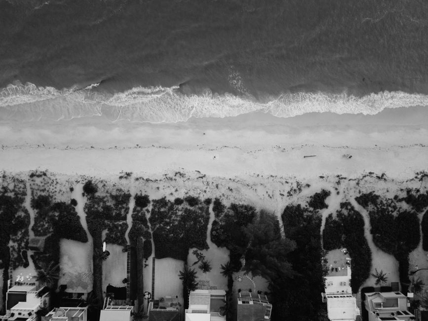 Stunning aerial view of a beach with waves approaching a row of beachfront houses, ideal for travel and nature imagery.