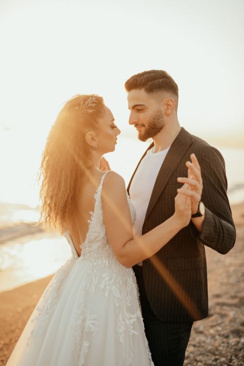 Free Bride and groom embracing on a sunlit beach, capturing love and joy. Stock Photo