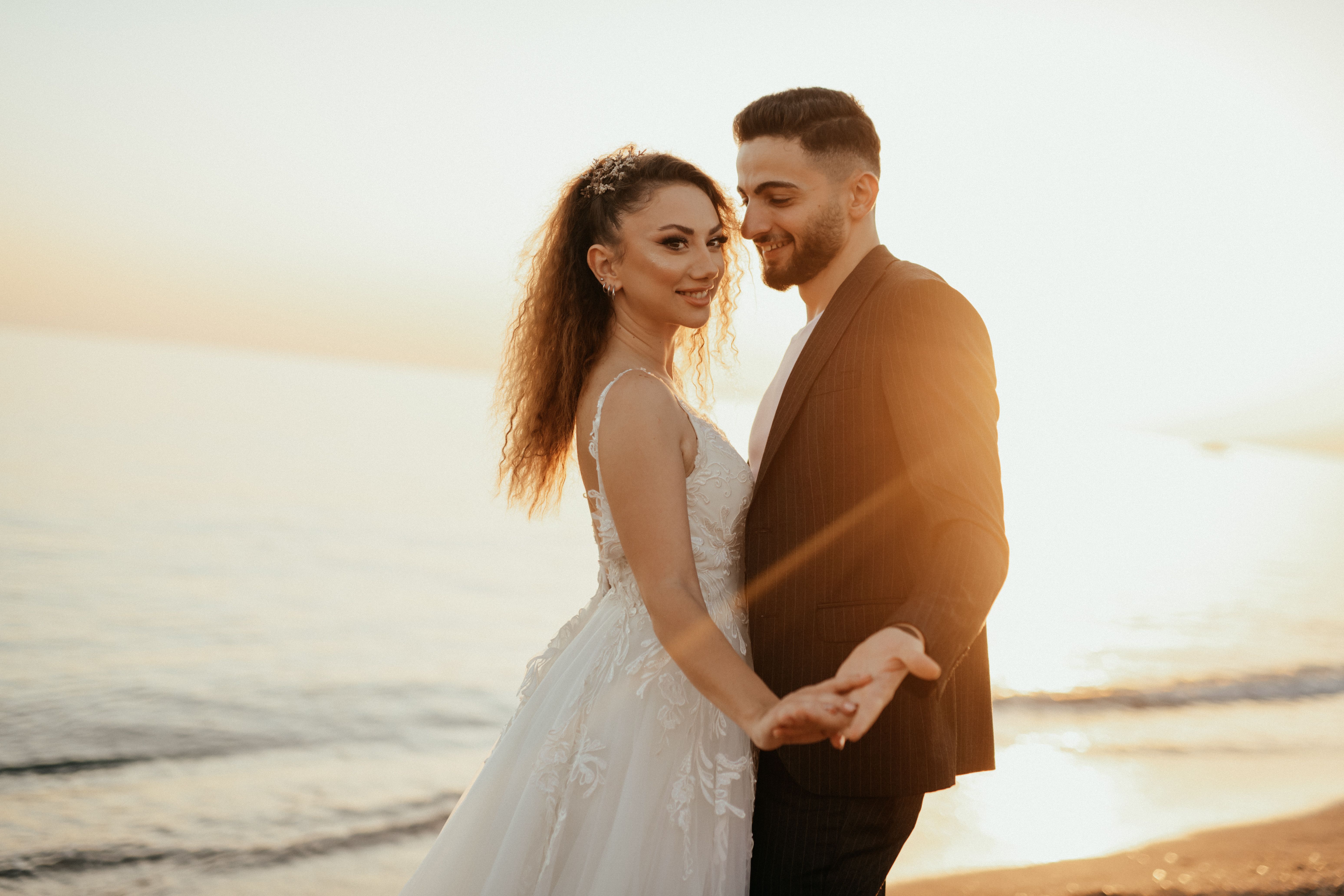 bride and groom portrait taken during golden hour, warm amber light, bride's dress catching the breeze, countryside setting