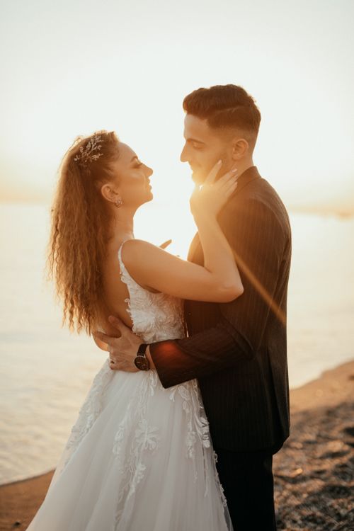 Free A loving couple embracing on a beach at sunset during their wedding day. Stock Photo