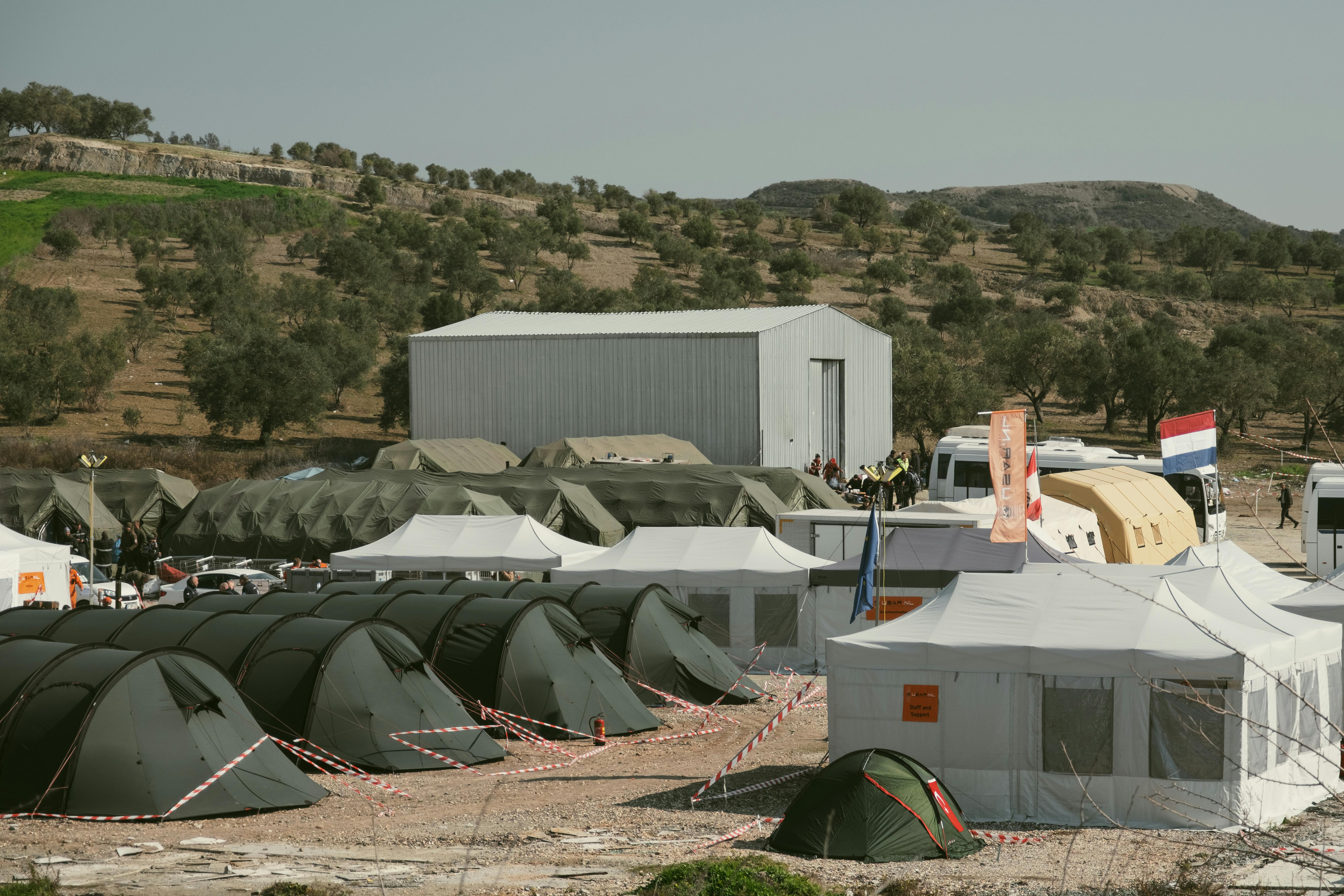 Aerial view of a temporary shelter camp in Antakya, Hatay, Türkiye, surrounded by olive trees.