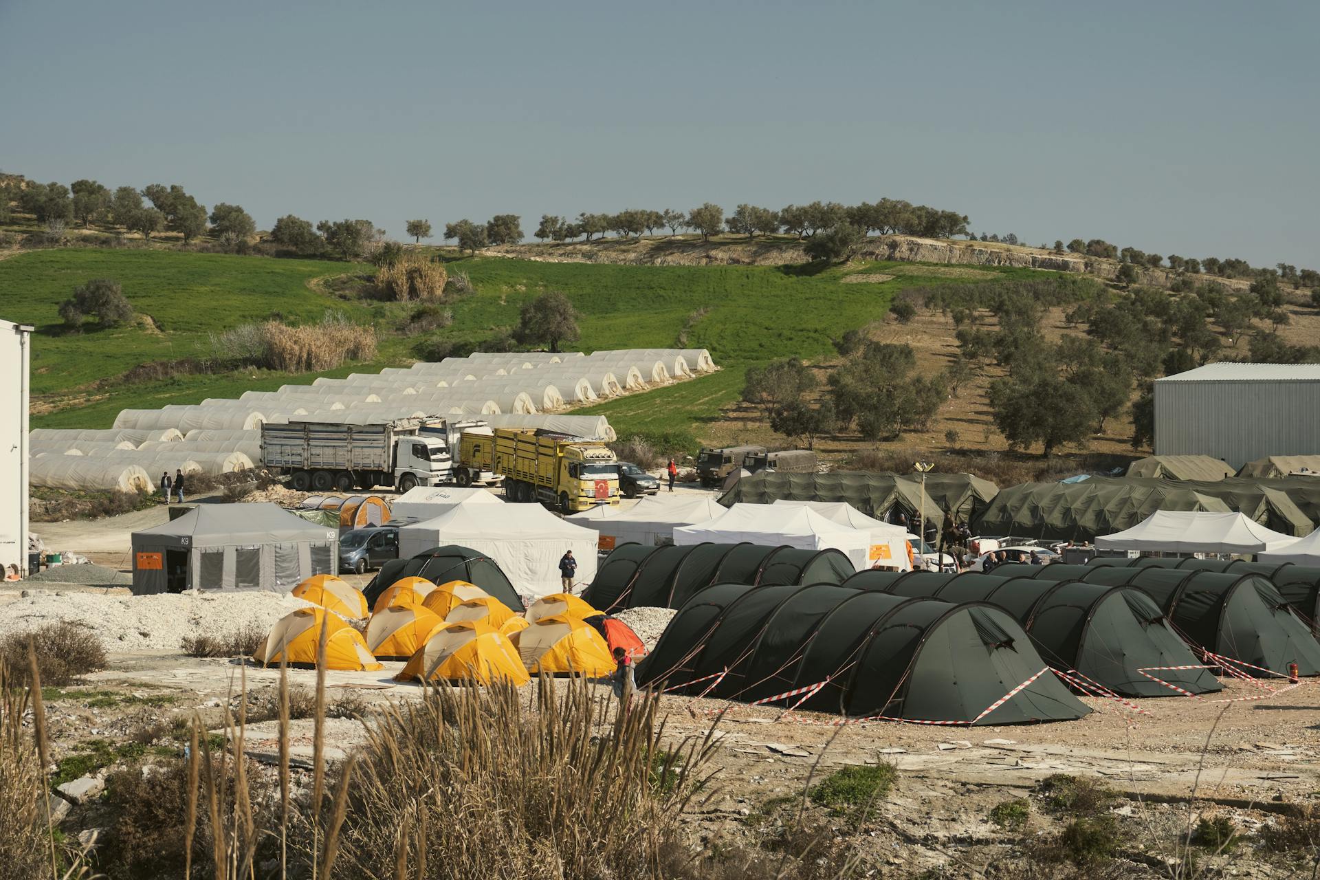 Aerial view of a temporary shelter campsite with colorful tents in Antakya, Türkiye, under a clear sky.