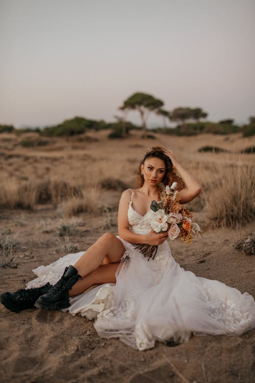 Bride in Wedding Dress Sitting on Grassland