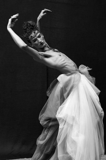 Artistic black and white fashion portrait showcasing a creative pose in a flowing fabric.