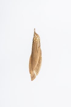 A beautifully crafted gold pendant with intricate fish design on a white background.