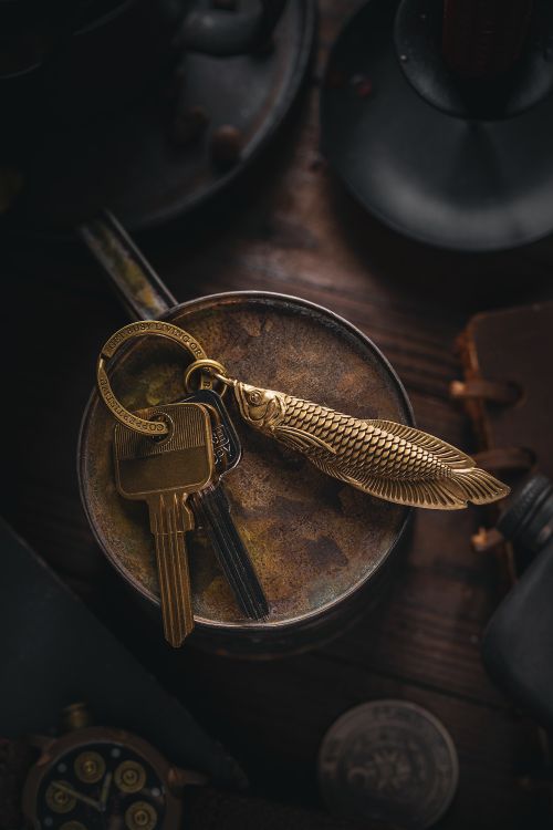 Free Close-up of a vintage keychain with a golden fish design on a rustic surface. Stock Photo