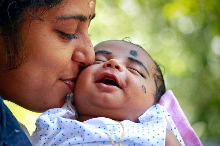 Close-Up Photo Of Mother Kissing Her Baby