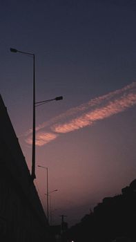 Silhouetted streetlights against a vibrant dusk sky in an urban setting, showcasing twilight beauty.
