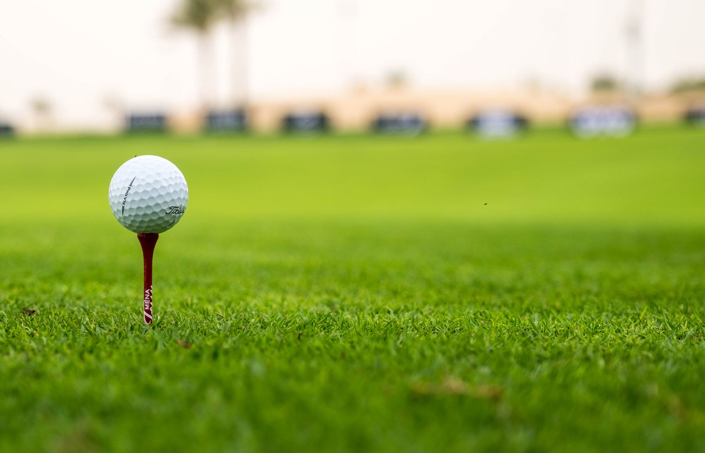 A close-up view of a golf ball on a tee set on a lush green golf course, perfect for sports enthusiasts.