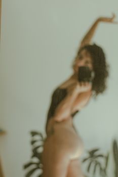 Creative blurred photo of a woman reflected in a mirror, capturing an artistic and sensuous vibe indoors.