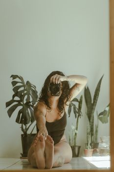 Woman in bodysuit photographing herself with camera in a cozy indoor setting.