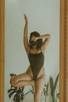 A woman poses in front of a mirror with body art, capturing an artistic self-portrait.