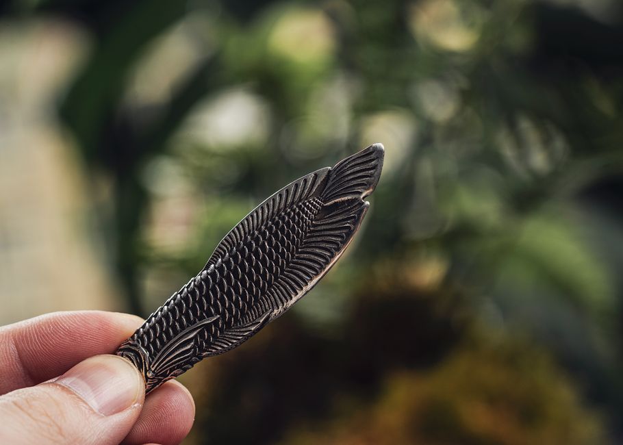 A small metal keychain pry tool held outdoors