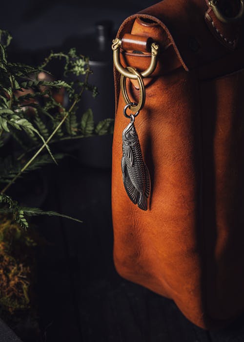 Steel Fish Pendant and Box Opener Hanging from a Leather Bag by the Fern