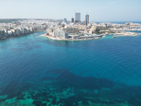 A stunning aerial view of Sliema's coastline, showcasing its modern architecture and vibrant blue Mediterranean Sea.